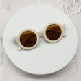 Load image into Gallery viewer, Off-white round sunglasses with brown-tinted lenses, showcased on a minimalistic white circular backdrop.