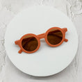 Load image into Gallery viewer, Terracotta orange round sunglasses featuring brown-tinted lenses, elegantly displayed on a white circular backdrop.