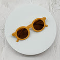 Load image into Gallery viewer, Round yellow sunglasses with brown lenses, stylishly placed on a minimal white circular surface.