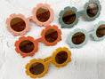 Load image into Gallery viewer, Assorted flower-shaped sunglasses with round lenses in peach, orange, mustard, and mint green frames, displayed on a textured white surface.