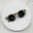 Load image into Gallery viewer, Beige round sunglasses with dark lenses, displayed on a minimalistic white circular platform.
