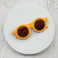 Load image into Gallery viewer, Round dark green sunglasses with brown lenses, elegantly placed on a minimalist white circular platform.
