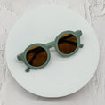 Load image into Gallery viewer, Round dark green sunglasses with brown lenses, elegantly placed on a minimalist white circular platform.
