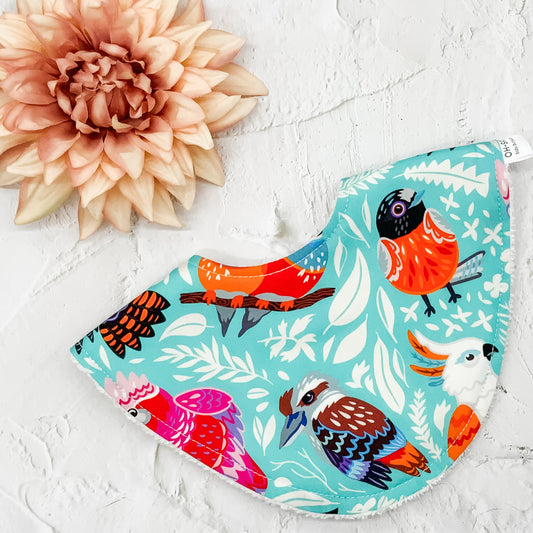 Australian Birds Dribble Bib – Handmade baby bib featuring a vibrant bird print on a turquoise background. Soft cotton front with absorbent towelling backing. Perfect for keeping babies dry and stylish.