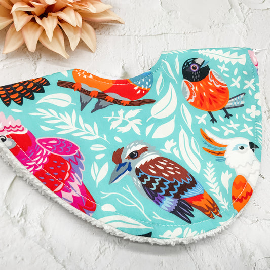 Australian Birds Dribble Bib – Handmade baby bib featuring a vibrant bird print on a turquoise background. Soft cotton front with absorbent towelling backing. Perfect for keeping babies dry and stylish.