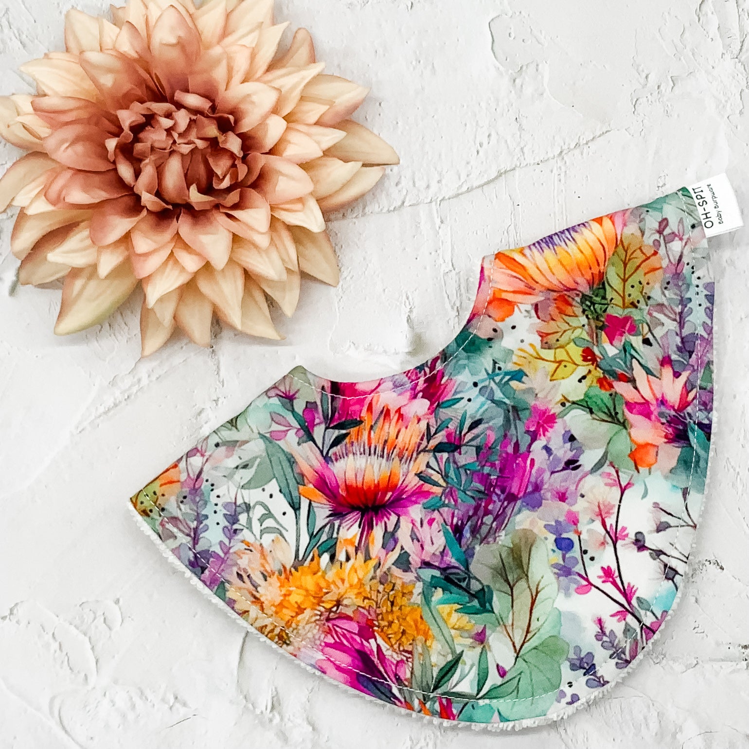Floral Dribble Bib – Handmade baby bib featuring a vibrant Australian native floral print. Made with a soft cotton front and absorbent towelling backing. Stylish and practical for everyday use.